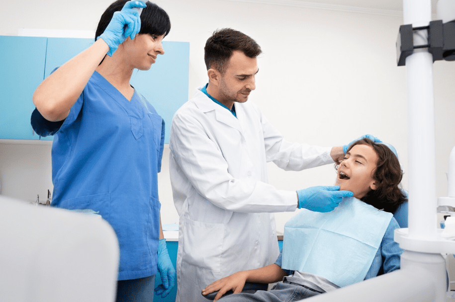 Dentist and dental assistant performing a check-up on a young patient in a dental chair, demonstrating General Dentistry care.
